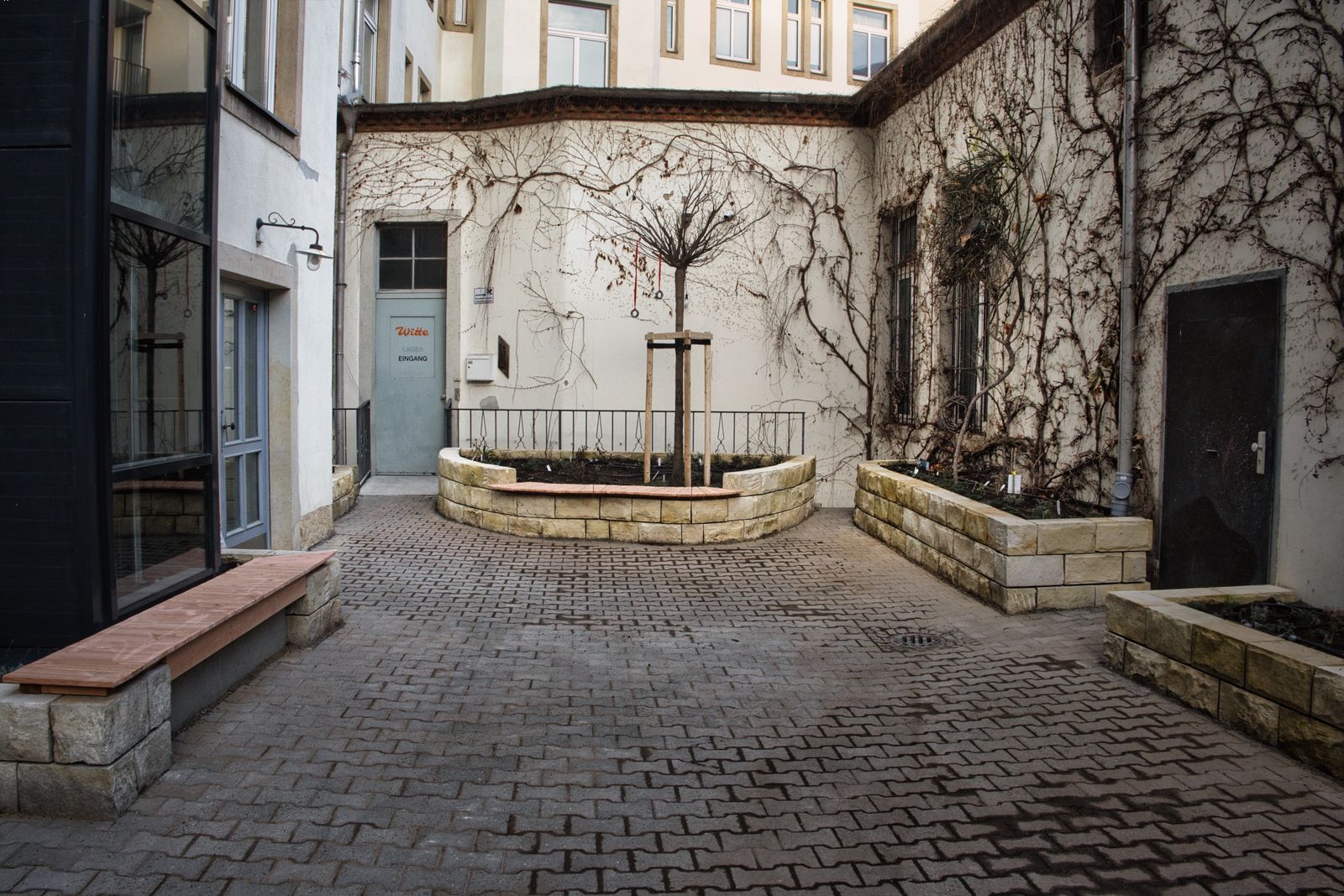 Fertig gestalteter Innenhof am Bahnhof Mitte mit Baum und Hochbeeten