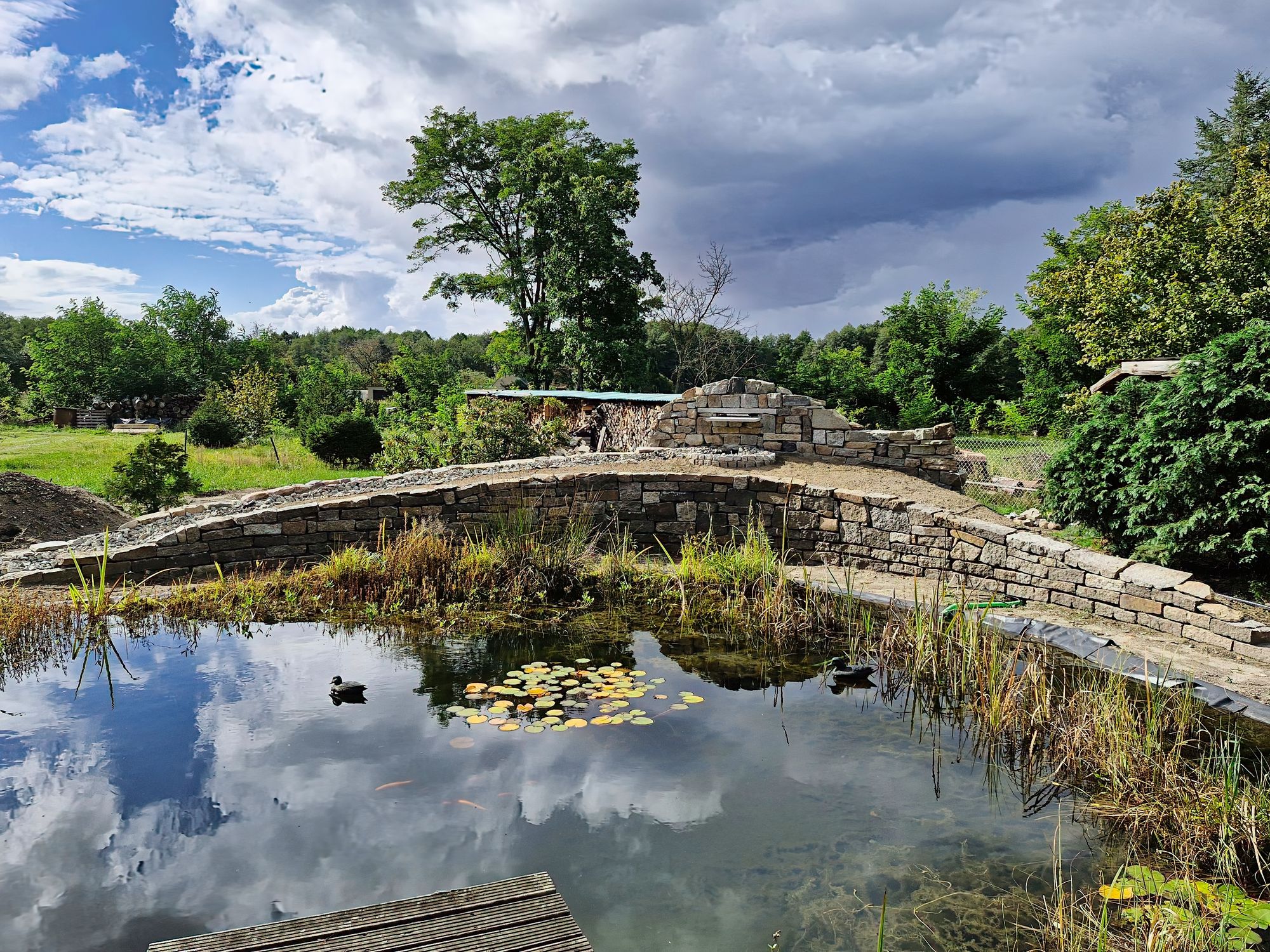 Naturnaher Schwimmteich mit Natursteinmauer